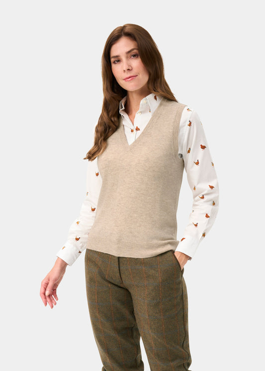 A woman wears the Erin Wool & Cashmere V-Neck Slipover in Porridge over a bird-print shirt and plaid trousers.
