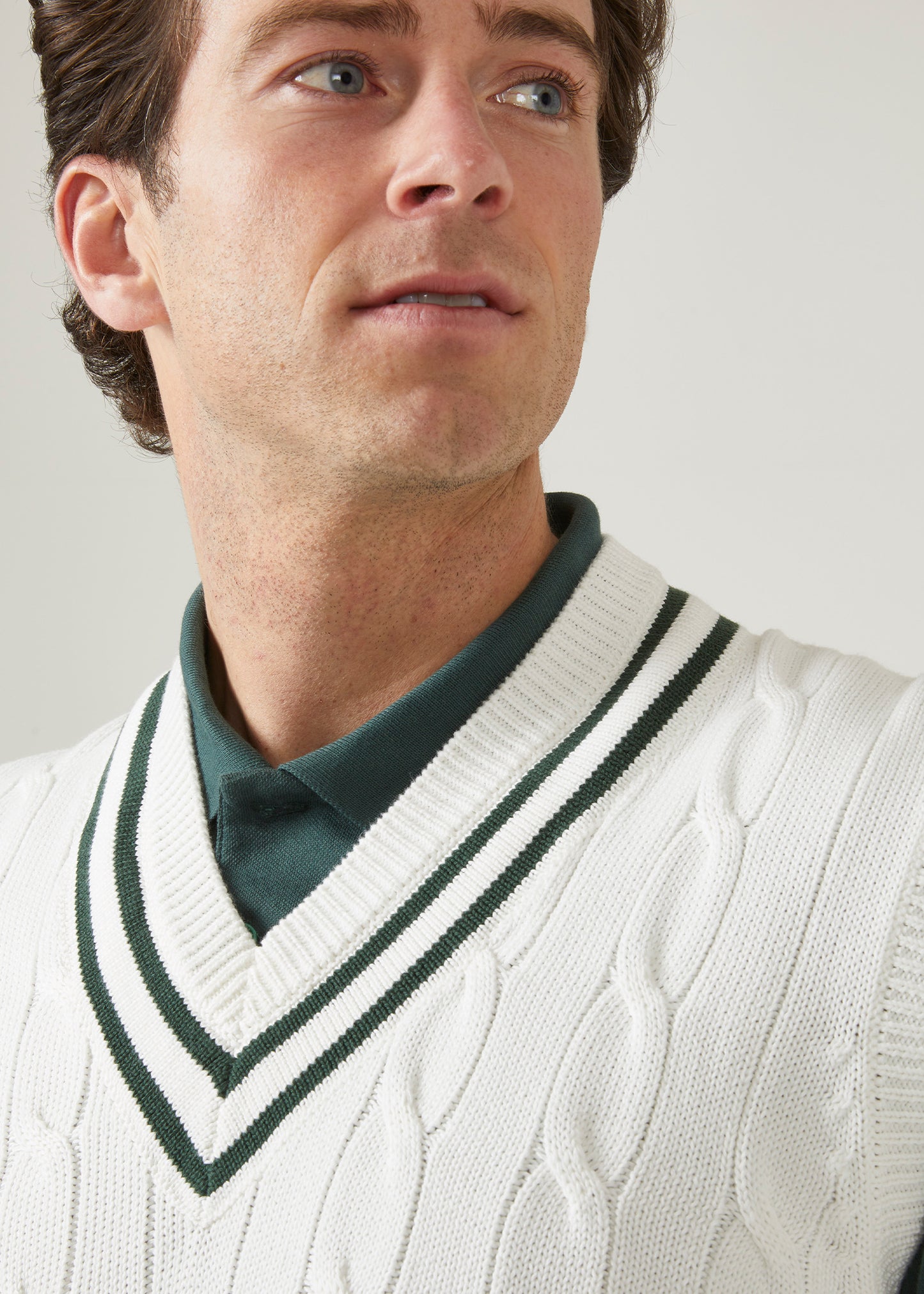 cable knit vee neck slipover in ecru with racing green trim.