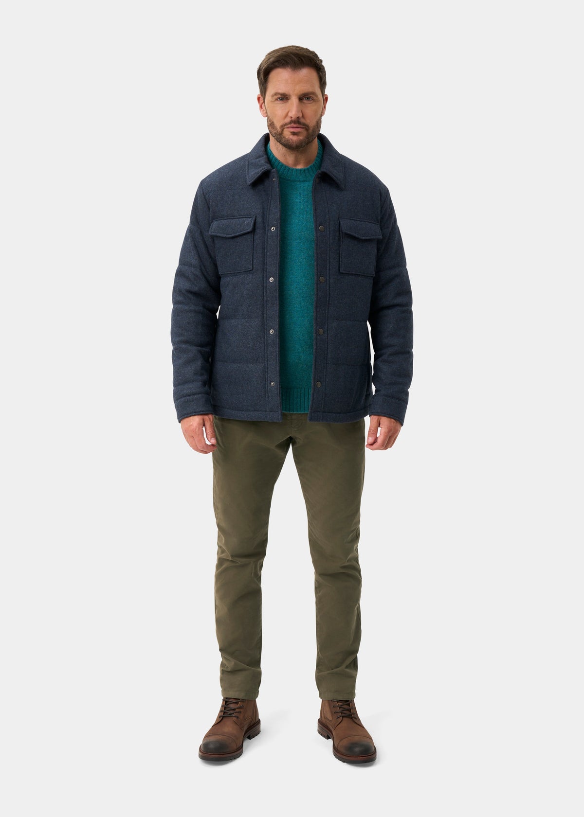 A man wearing a Richmond Men’s Knitted Quilted Shacket In Navy over a teal sweater, olive trousers, and brown leather boots.