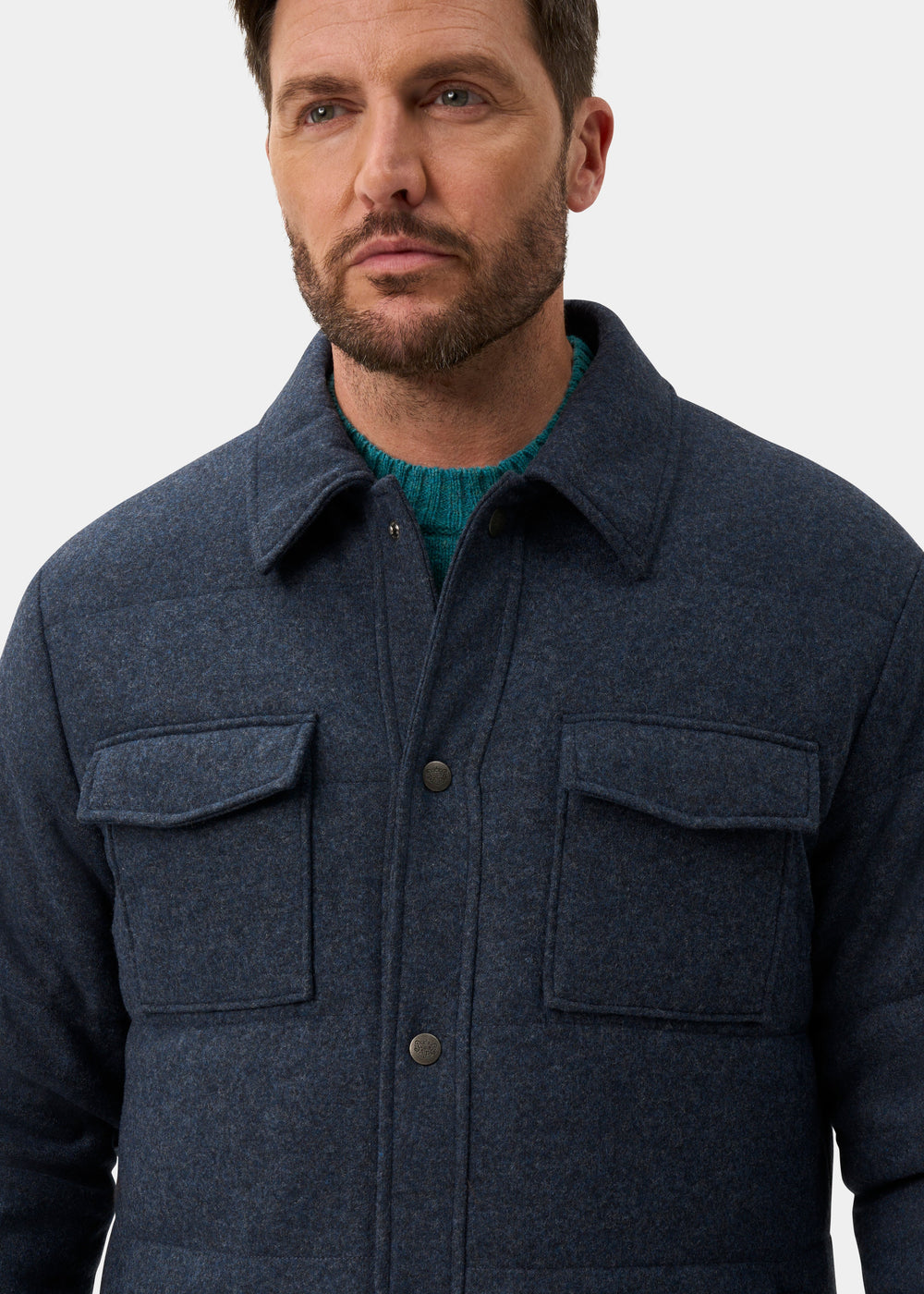 A man wears a Richmond Men’s Knitted Quilted Shacket In Navy over a green sweater.