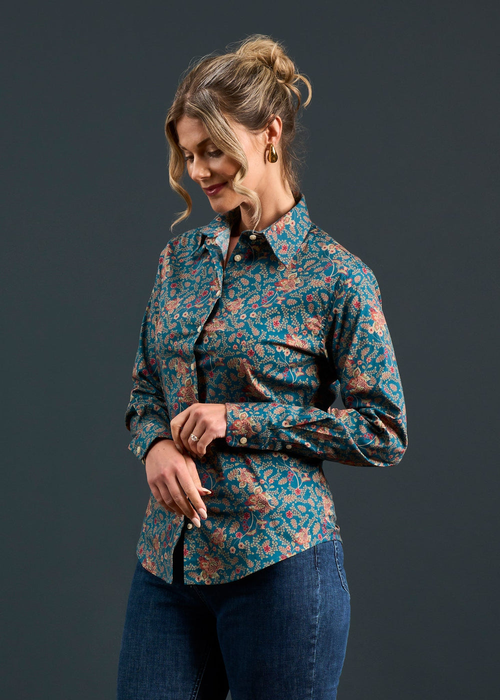 Blonde woman in a bun wears Lawen Cotton Printed Shirt in Blue Floral Design, paired with jeans, against dark background.