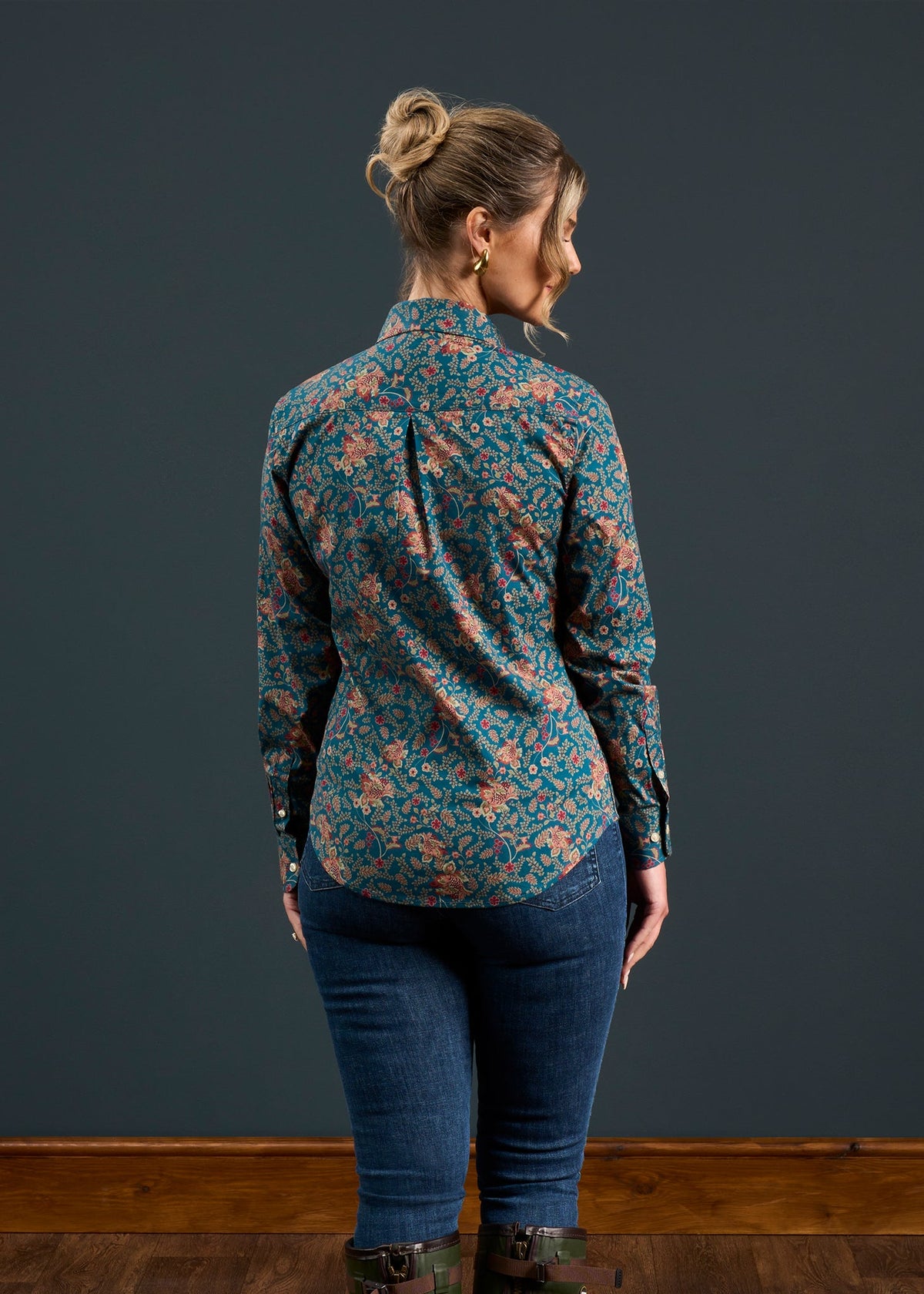Woman in a bun wears the Lawen Cotton Printed Shirt in Blue Floral Design, back facing camera, with jeans.