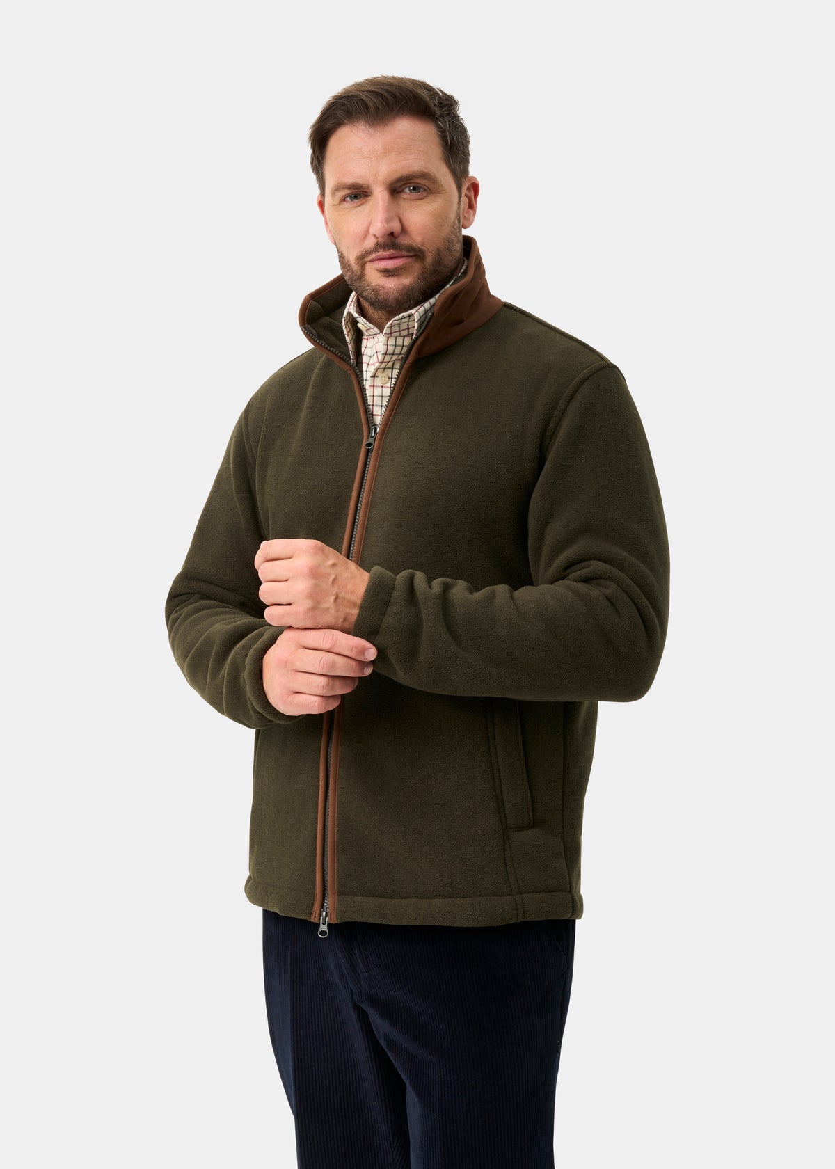 Man wears green Aylsham Men’s Fleece Jacket, regular fit, over a plaid shirt against a plain background.