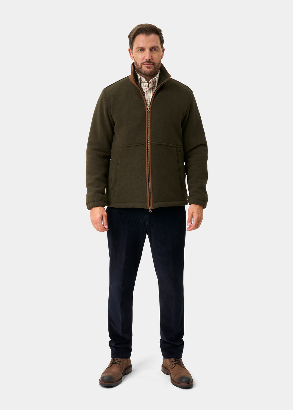 Man in Aylsham Men’s Fleece Windblock in green over plaid shirt, navy pants, brown boots; light gray background.