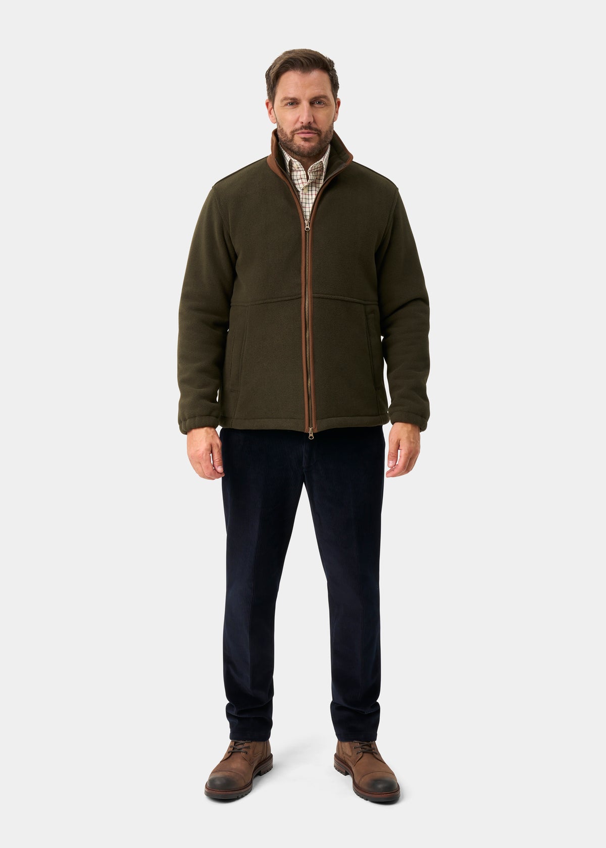 Man in Aylsham Men’s Fleece Windblock in green over plaid shirt, navy pants, brown boots; light gray background.