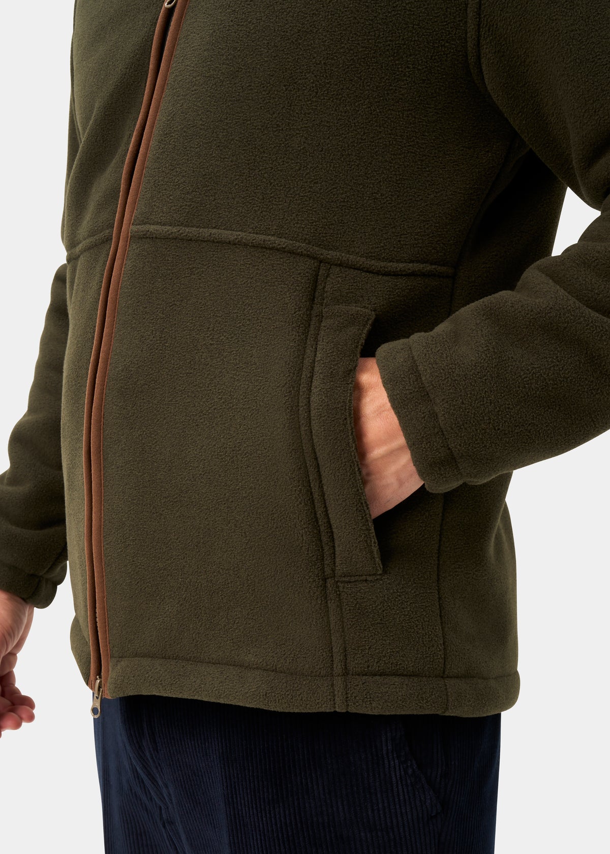 A man wears the Aylsham Men’s Fleece Windblock in green, brown zip, one hand pocketed, shown chest-down.