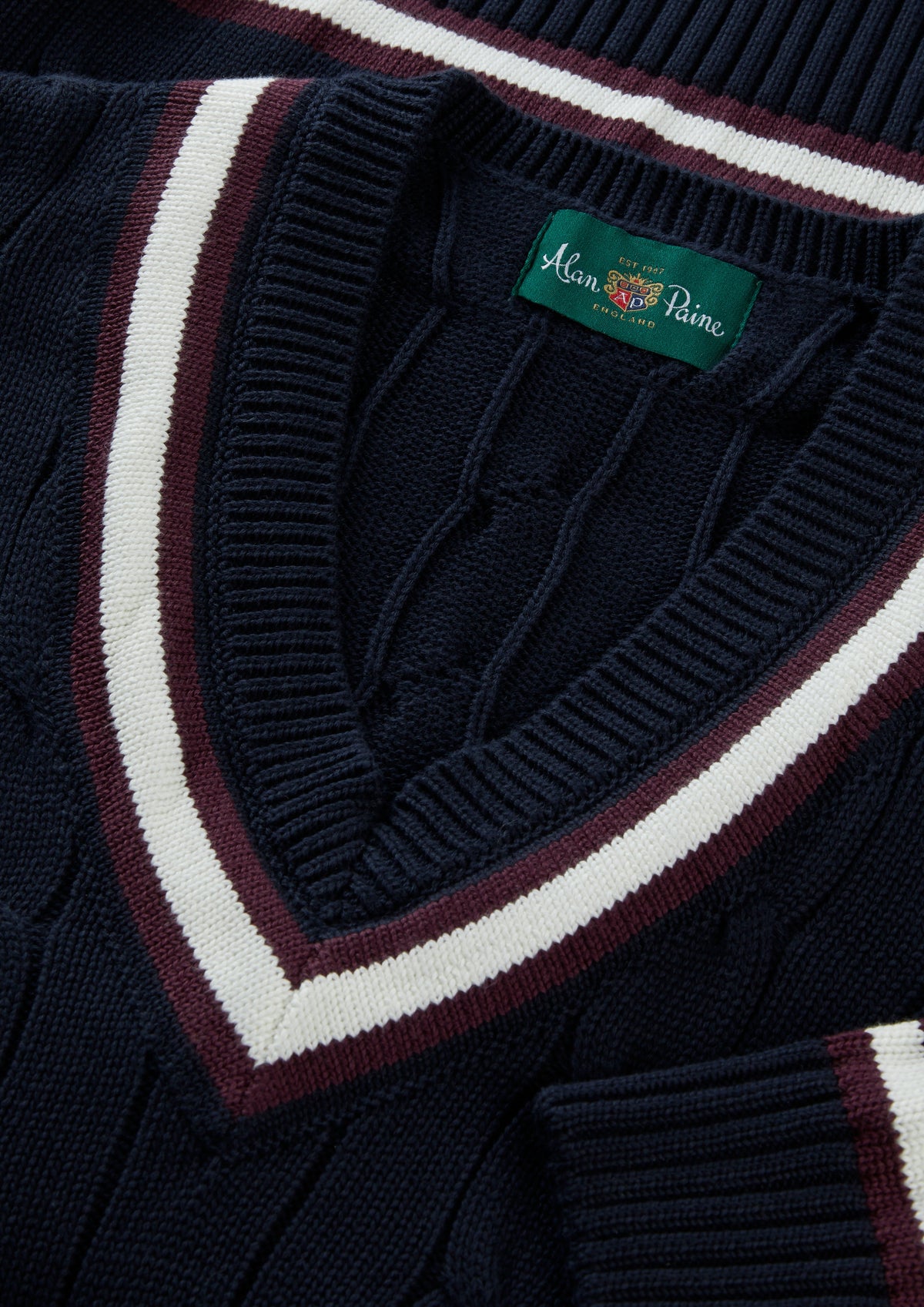 Sandridge Cotton Cable Knit V-Neck Cricket Jumper in dark navy with a V-neck and burgundy and white striped trim.