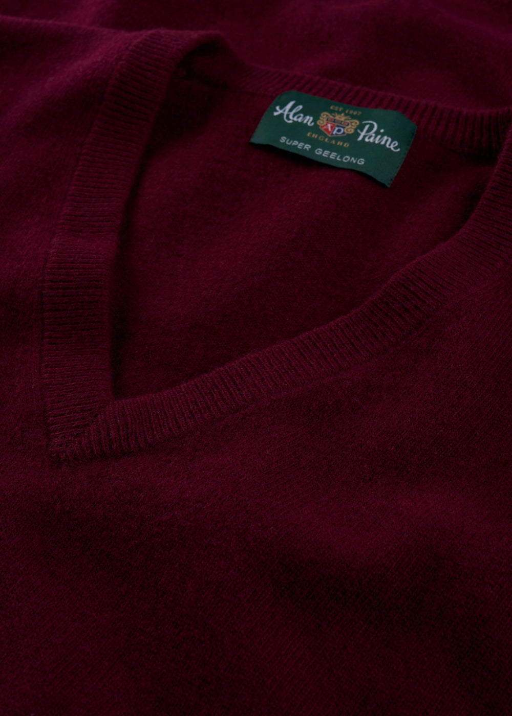 Close-up of the Albury Geelong Wool V-Neck Jumper in Claret, Regular Fit, showing label at collar.