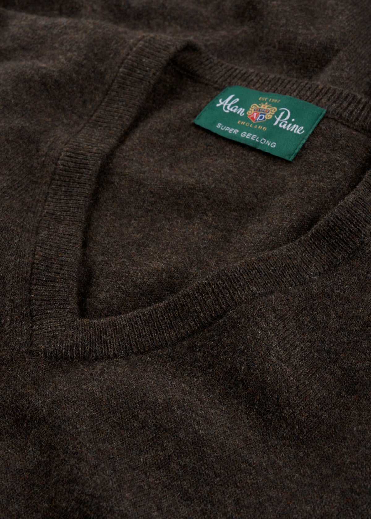 Close-up of Albury Geelong Wool V-Neck Jumper in Cocoa, regular fit, featuring Alan Paine label on a green tag.