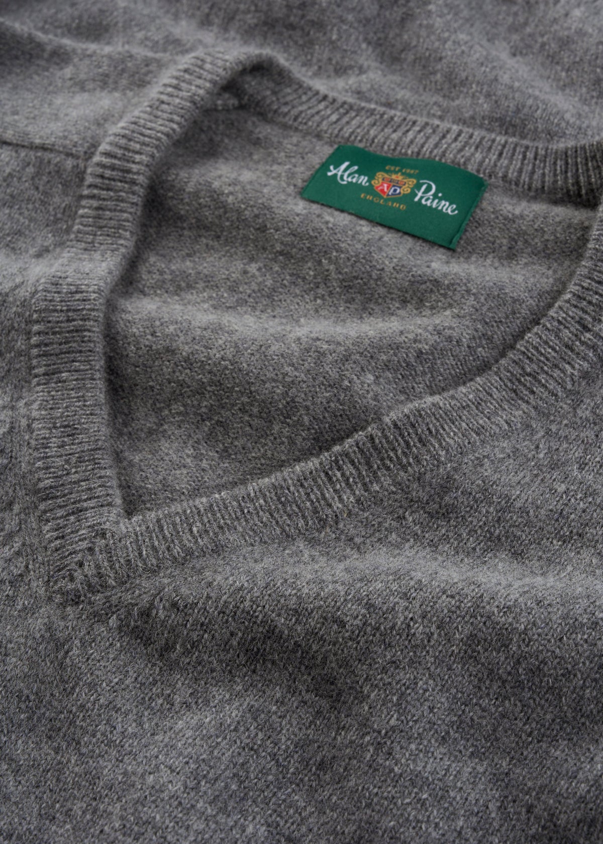 A grey Hampshire Lambswool V-neck jumper, classic fit, with a green Alan Paine England label inside the collar.