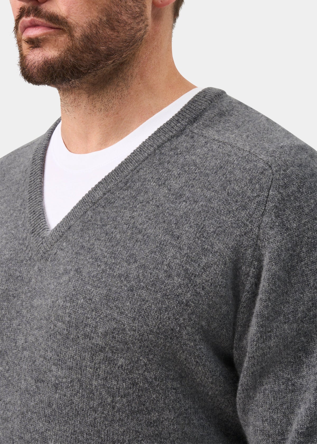 Man wears Hampshire Lambswool V-Neck Jumper in Grey Mix, classic fit, over a white shirt against plain background.