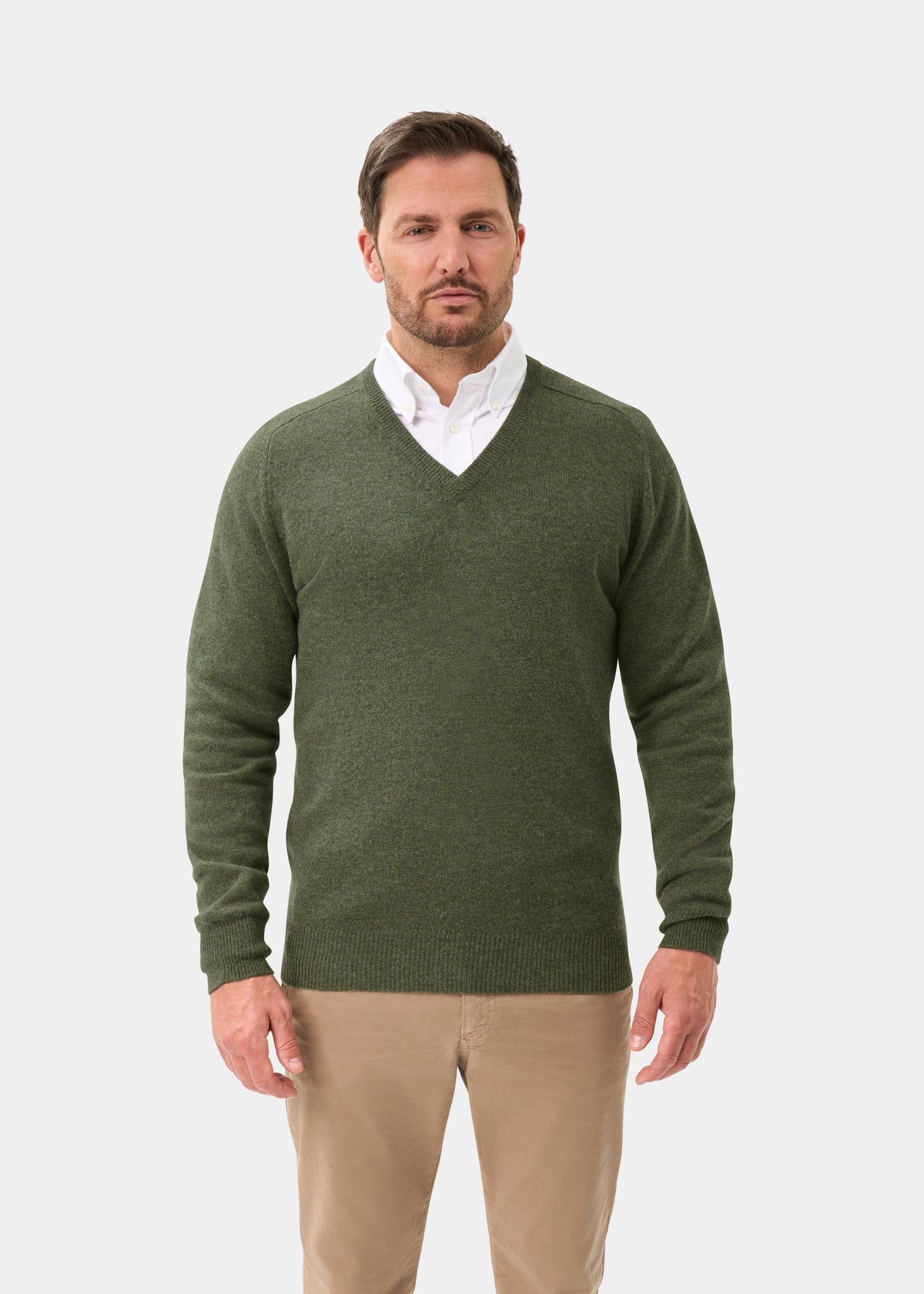 Man in Hampshire Lambswool V-Neck Jumper in Landscape over a white shirt, khaki pants, against plain background.
