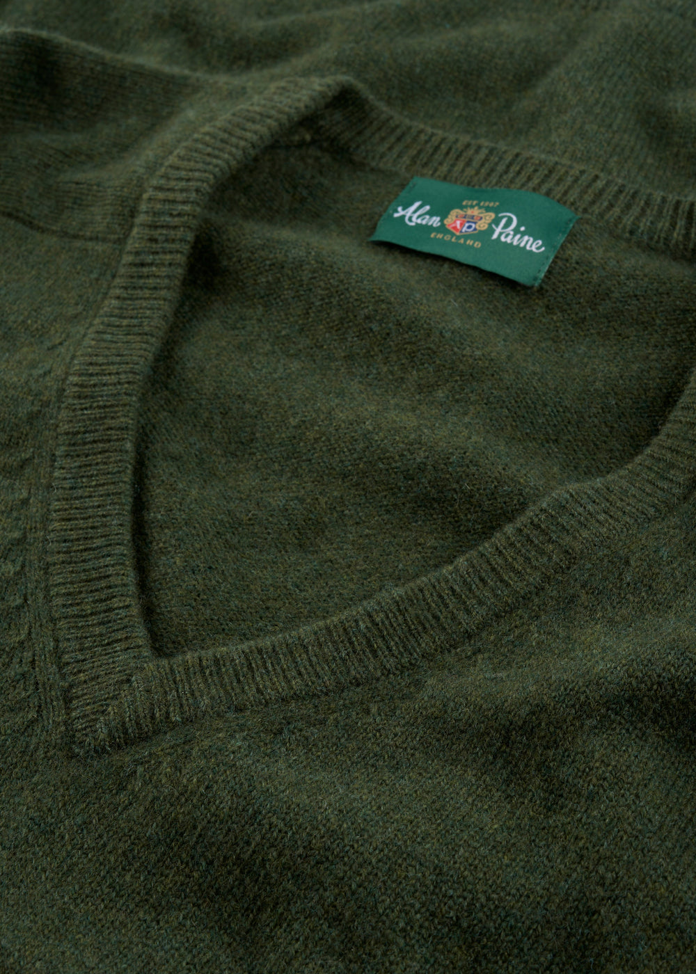 Close-up of Hampshire Lambswool V-Neck Jumper in Rosemary, classic fit, with label at the collar.