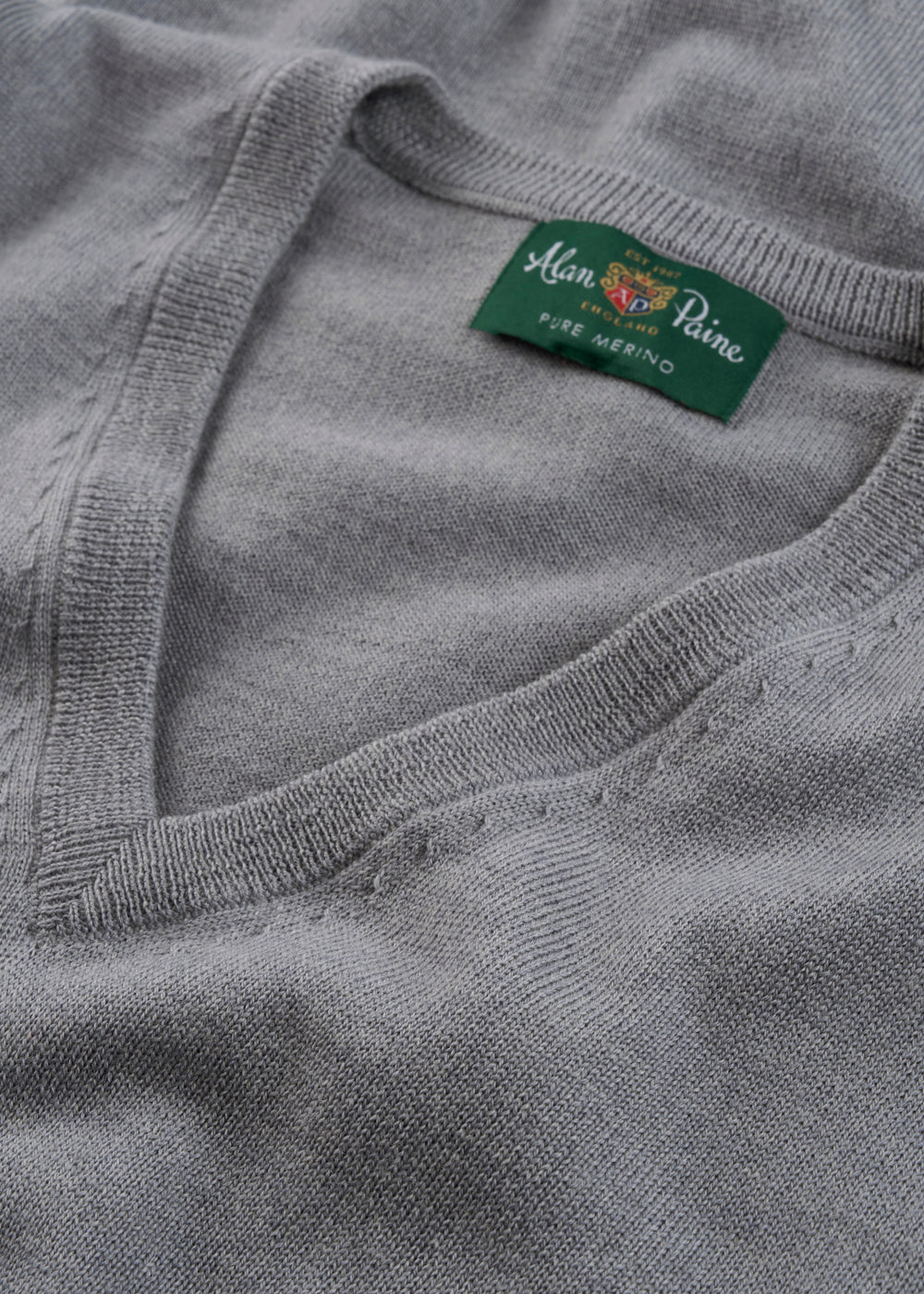 Gray sweater with a brand label on a close-up of the neckline.