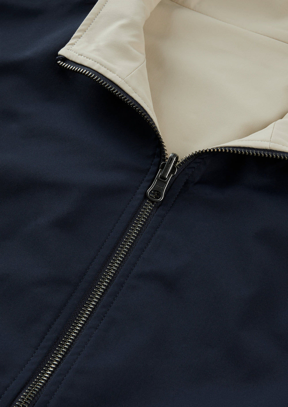 Close-up of Lakeward Men’s Reversible Bomber Jacket in navy and beige with a silver zipper and water-resistant finish.