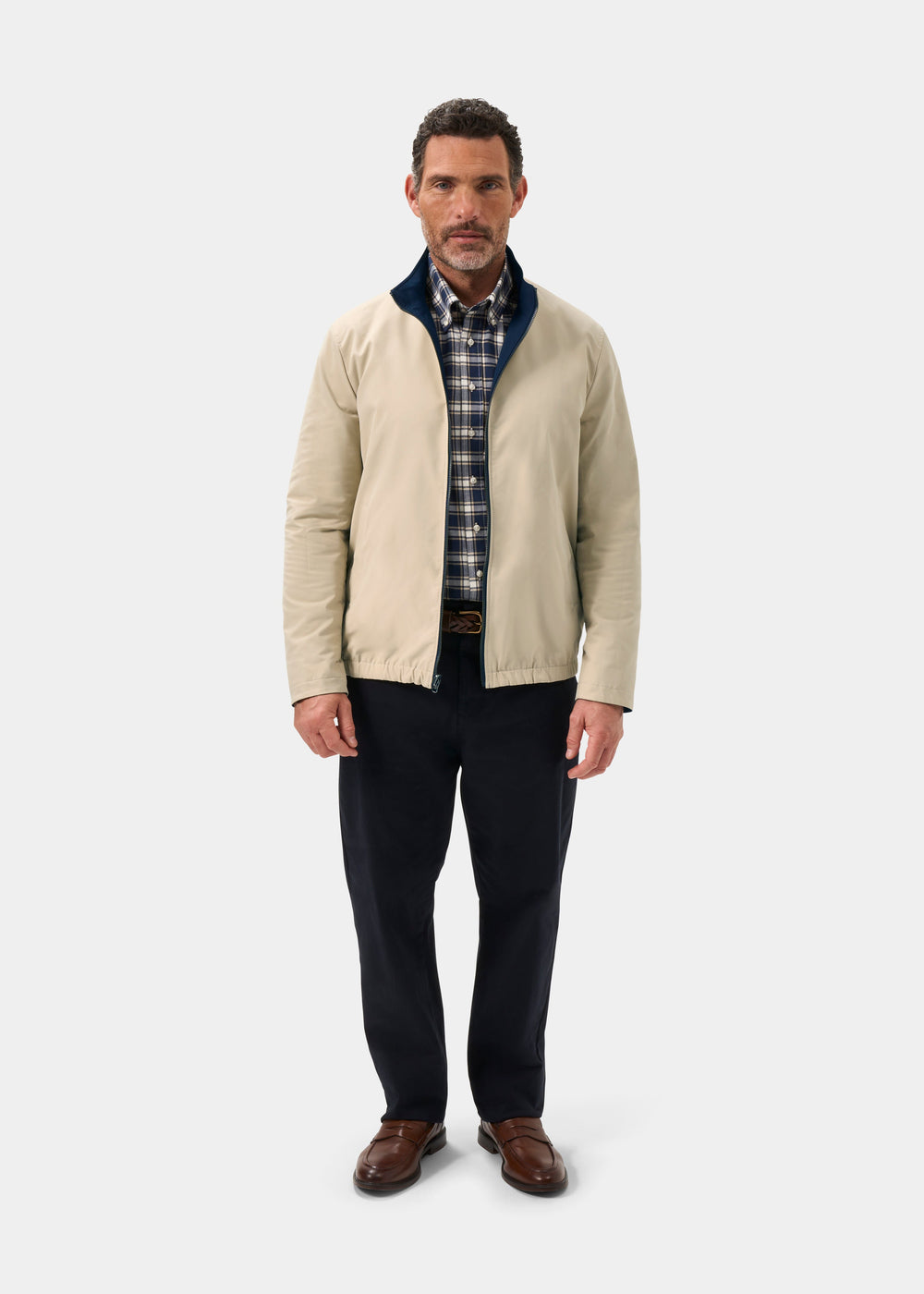 Man in Lakeward Men’s Reversible Bomber Jacket (Navy/Beige), plaid shirt, dark pants, brown shoes on white background.