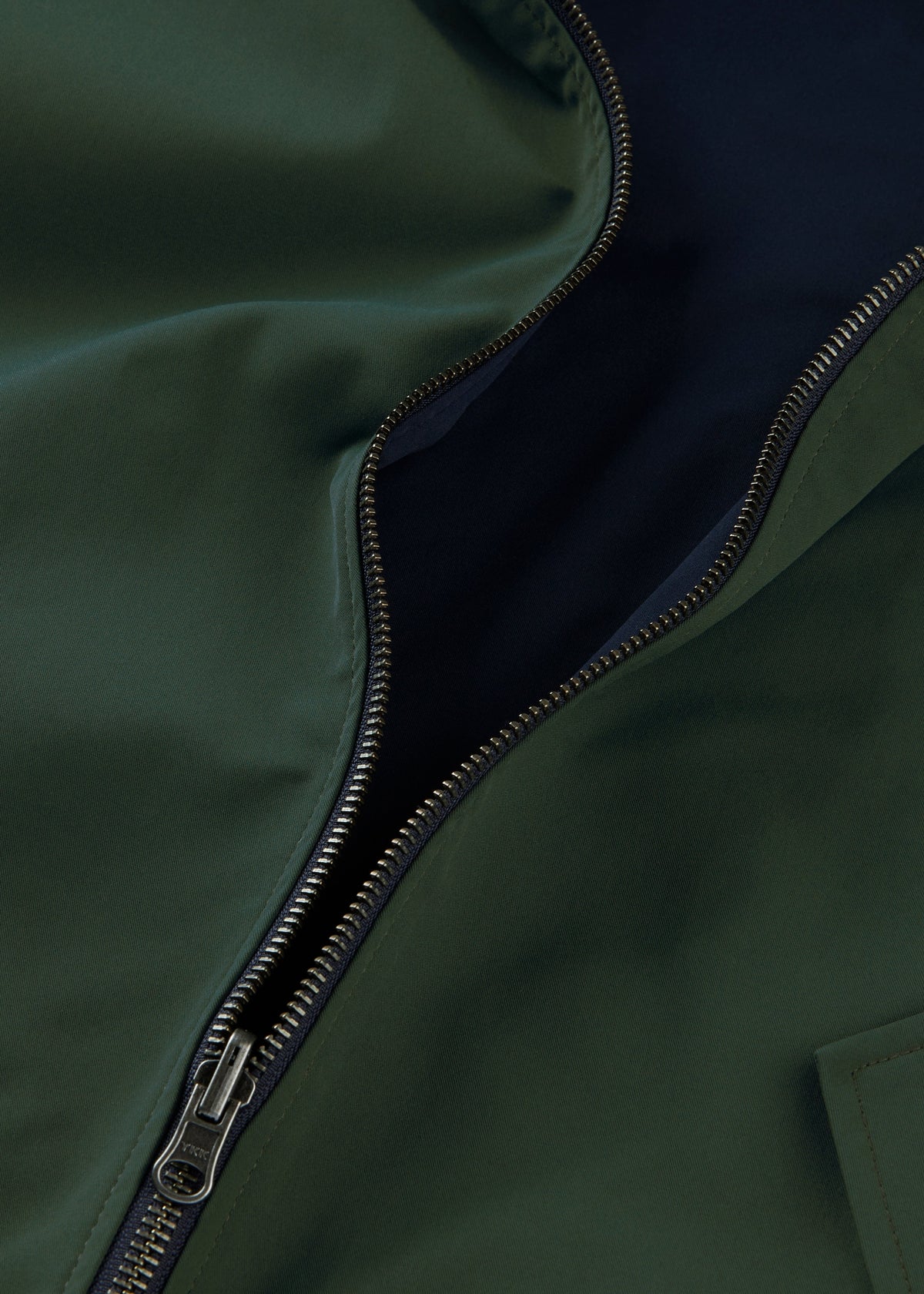 Close-up of a Lakeward Men’s Reversible Bomber Jacket, partially unzipped, showing navy lining and metallic zipper.