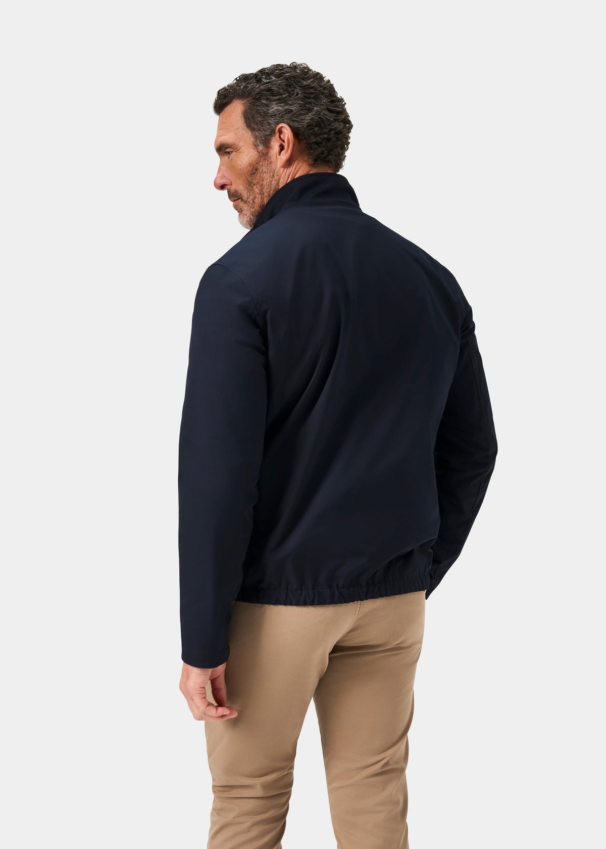 Man with short curly hair wears the Lakeward Men’s Reversible Bomber Jacket in navy, standing against a white background.
