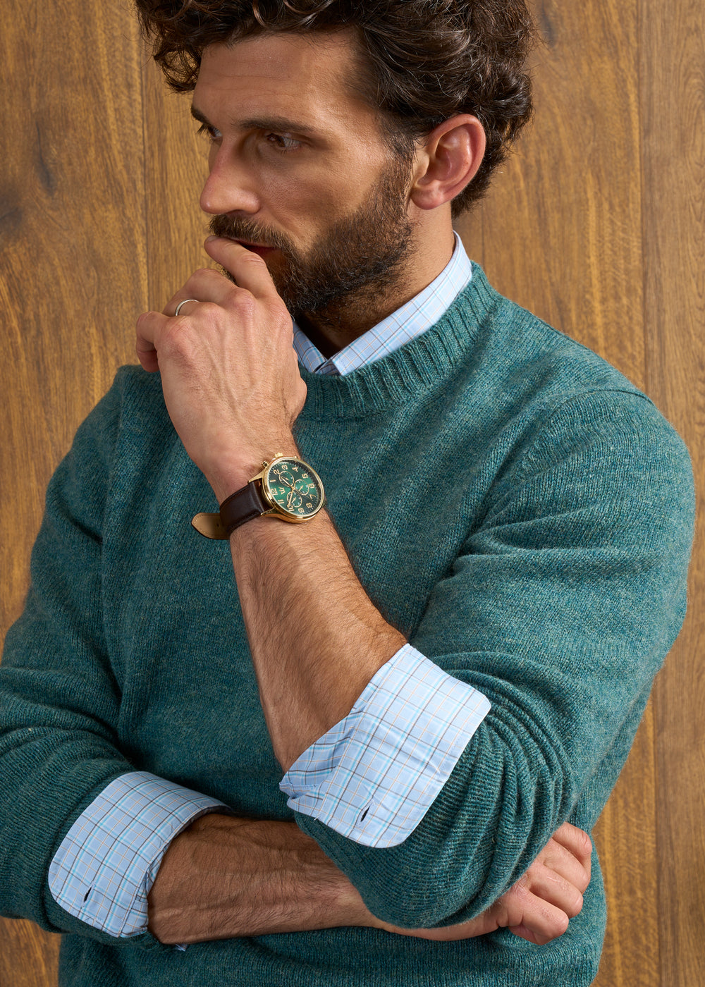 Man in a Kingfisher Kinnadie Shetland jumper and checked shirt poses, hand on chin, gold watch showing.