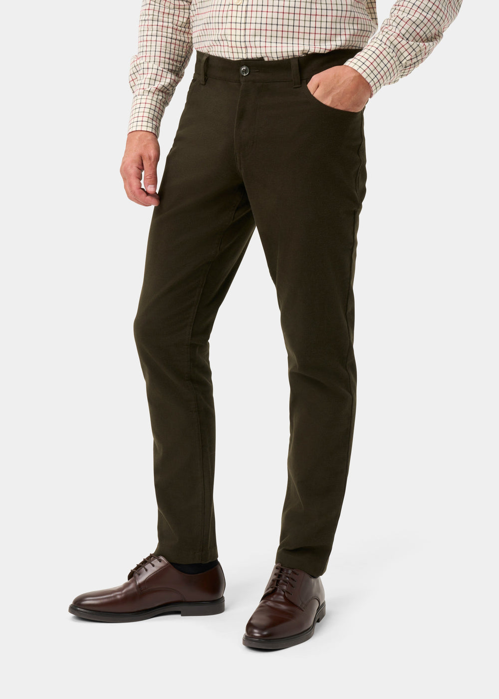 A person wearing slim-fit dark olive green trousers, a beige and red checkered shirt, and dark brown leather dress shoes, shown from the waist down on a light gray studio background.
