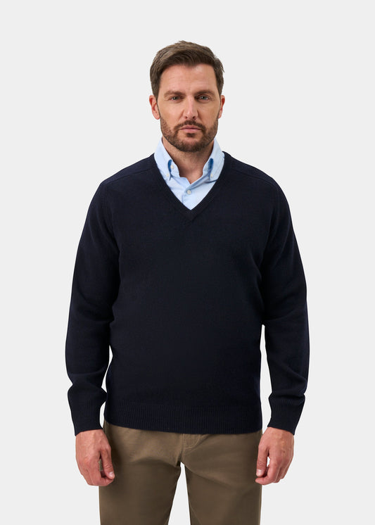 Alan Paine navy lambswool V-neck jumper with saddle shoulders worn by a man over a light blue shirt