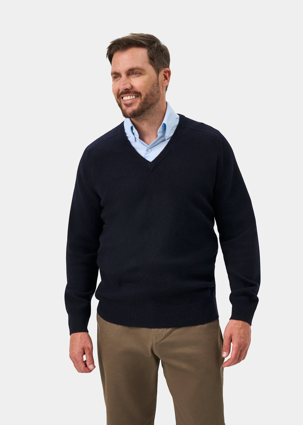 A man wearing an Alan Paine navy lambswool V-neck jumper over a light blue shirt, featuring a classic fit.