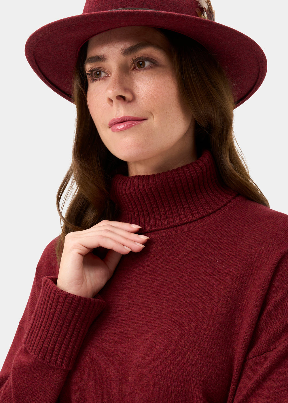 Woman in the Alexa Roll Neck in Berry, gazing softly to the side, wearing a matching hat.