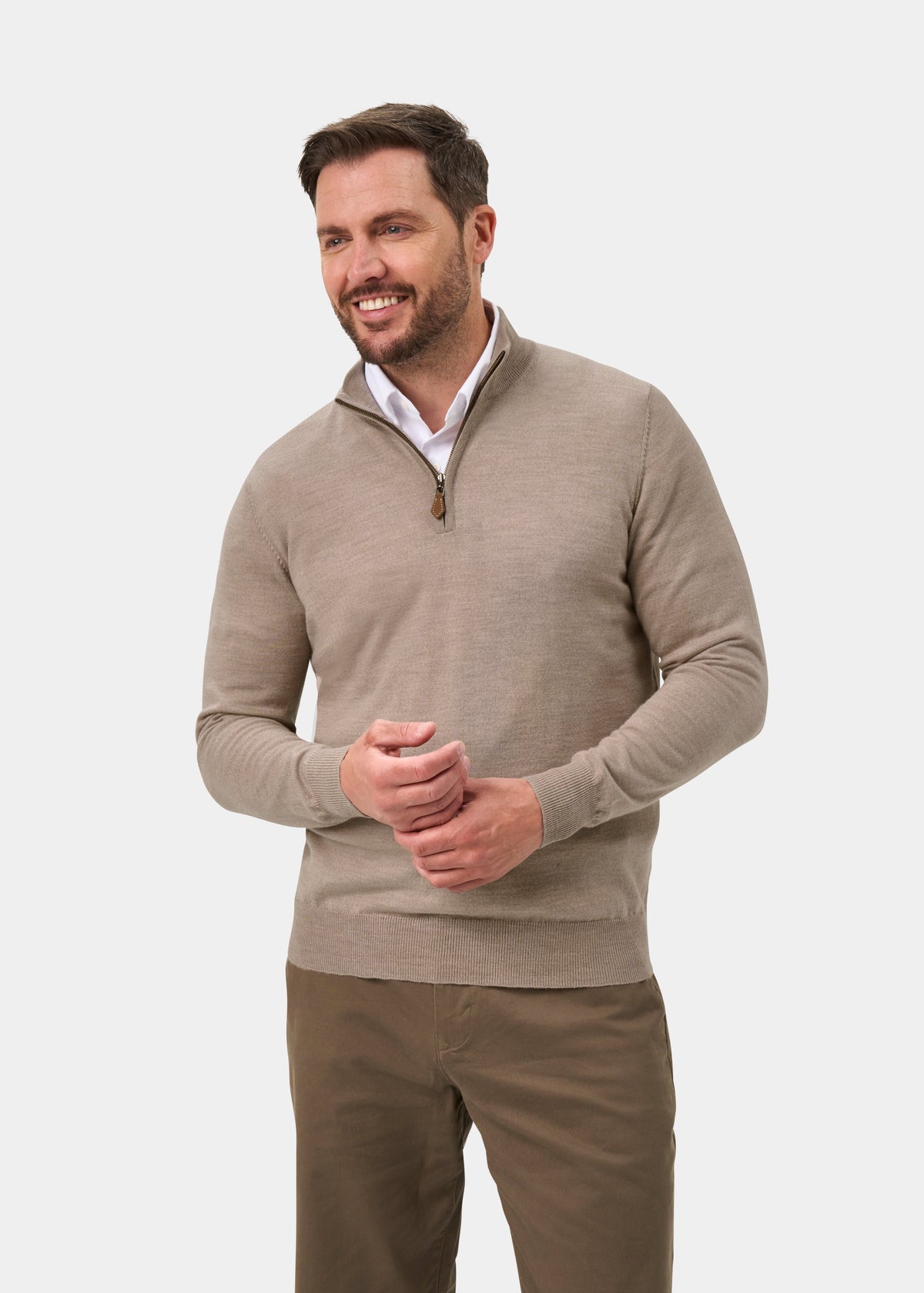 Man smiling in Barton Merino Wool Quarter Zip Jumper in Cobble over white shirt, brown pants, on white background.