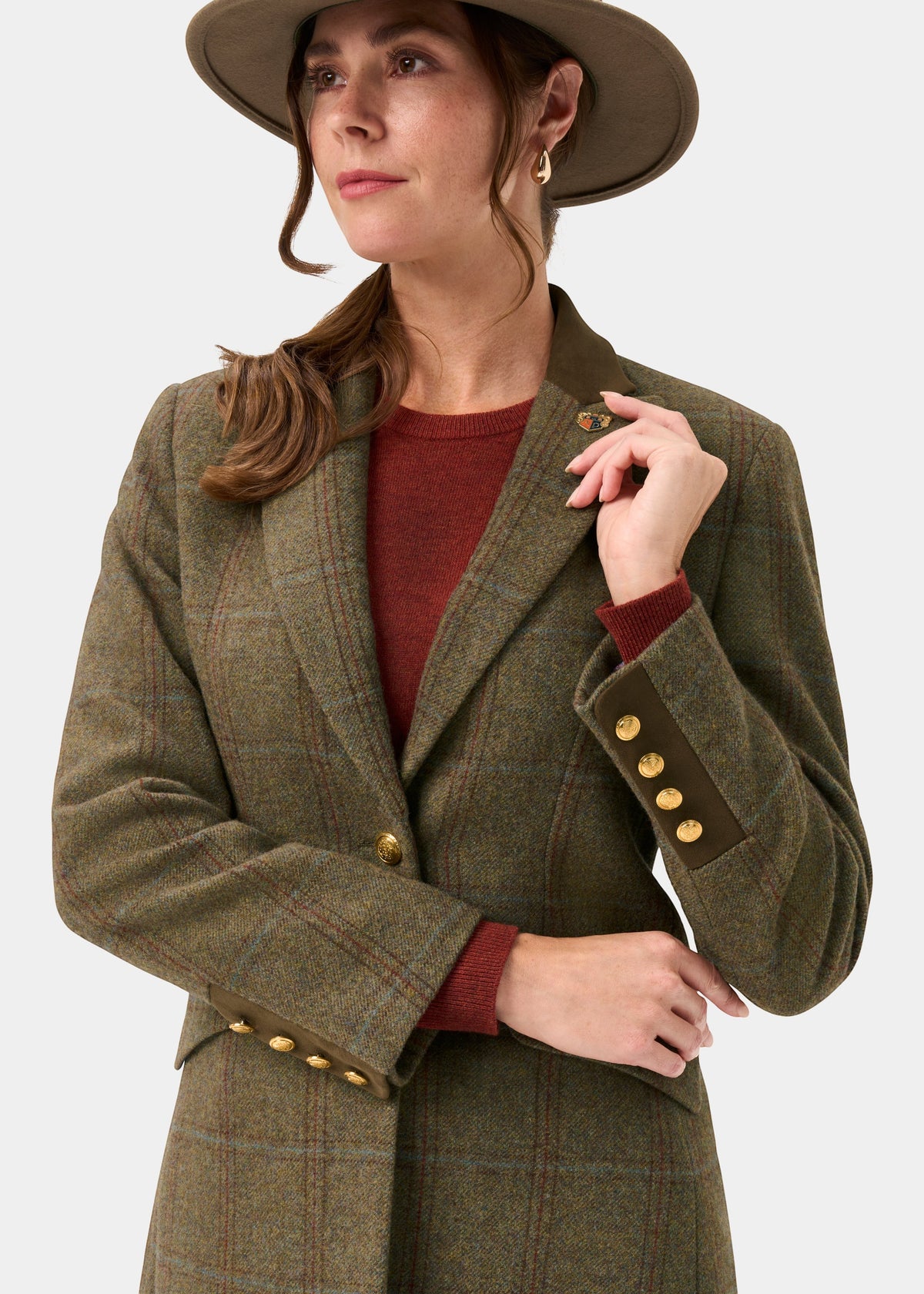 Woman in Combrook Ladies Tweed Water Repellent Mid-Thigh Coat in Laurel, wide-brim hat, looking to the side.