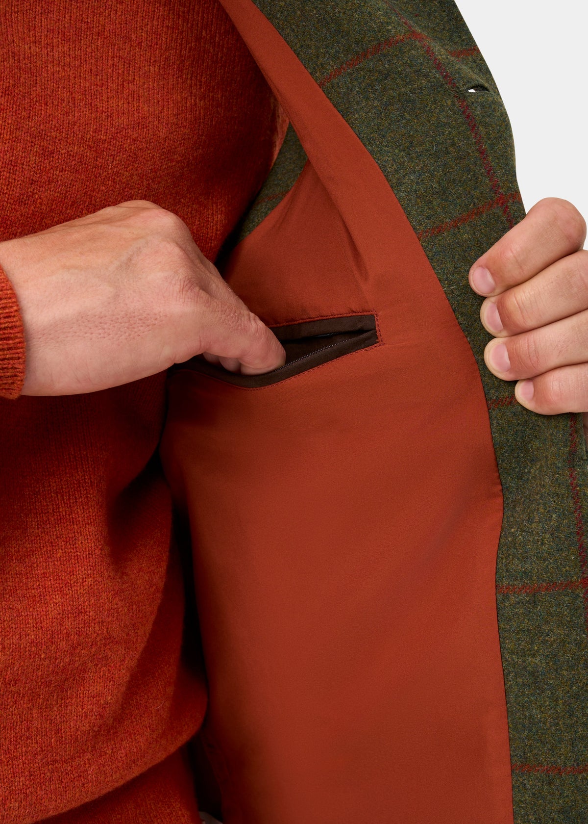A person slips their hand into the inner pocket of a Combrook Men’s Tweed Water Repellent Gilet in Reed.