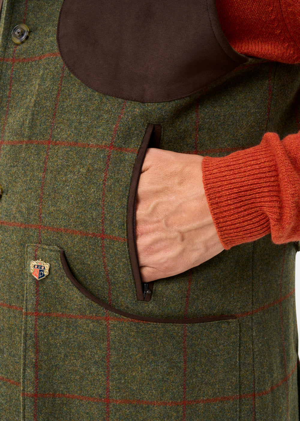 A close-up of a person in a Combrook Men’s Tweed Shooting Gilet in Reed with suede shoulder patch and red checks.