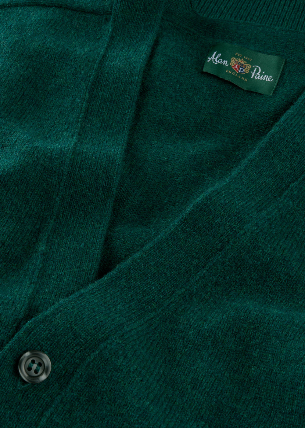 Close-up of Cornwall Lambswool V-Neck Cardigan in Mallard, classic fit, showing a black button and inside label.