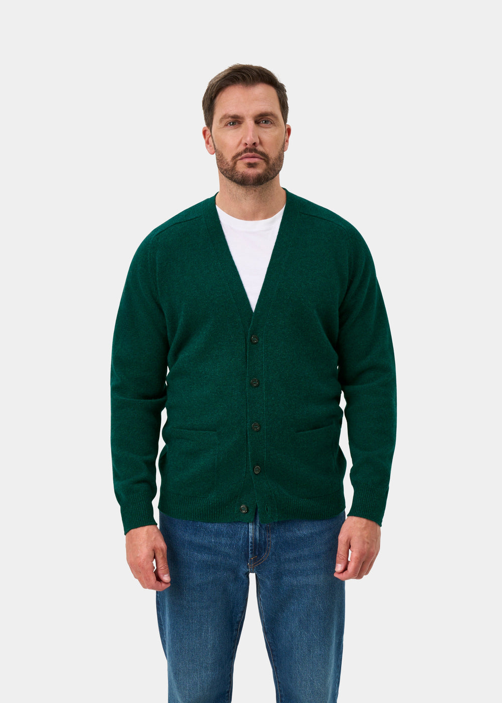 Man in Cornwall Lambswool V-Neck Cardigan in Mallard, white shirt, and blue jeans against a plain background.