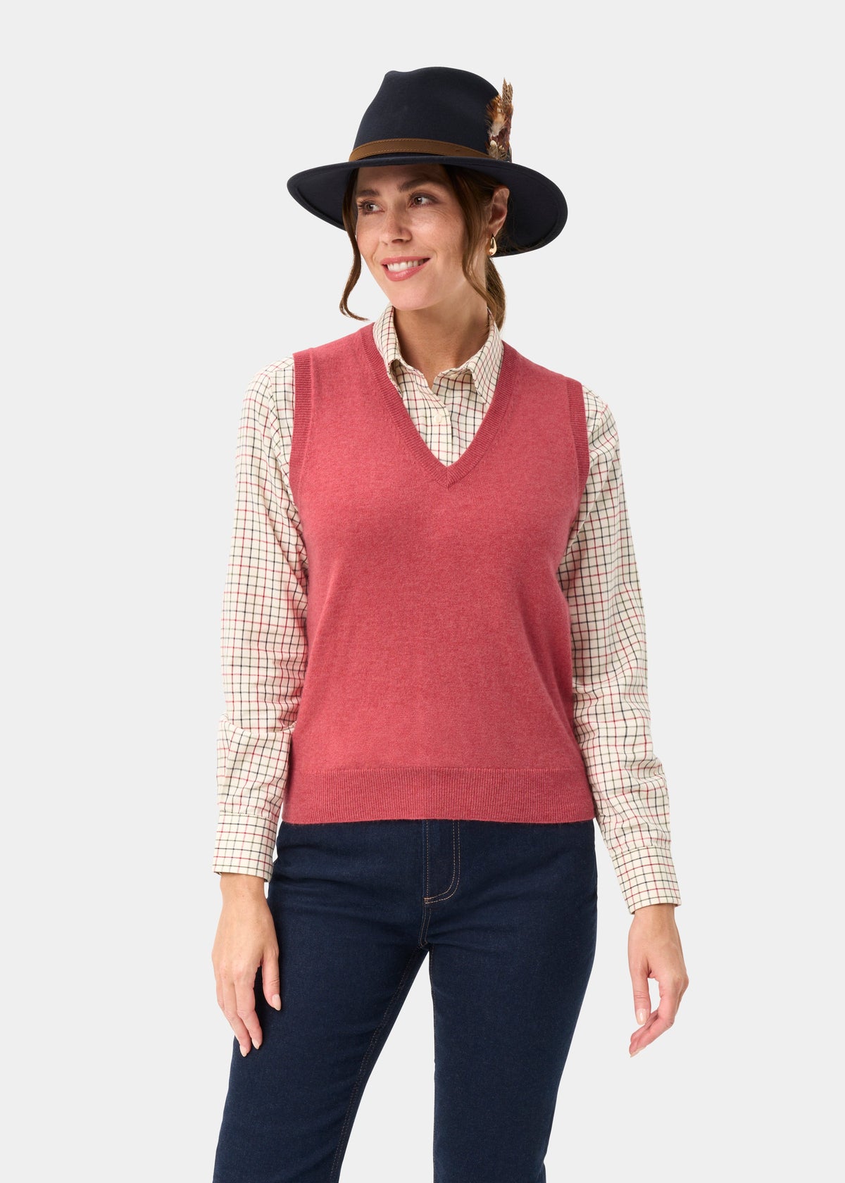 Woman in a checked shirt, Erin Wool & Cashmere V-Neck Slipover in Rouge, dark hat with feather, and dark pants.