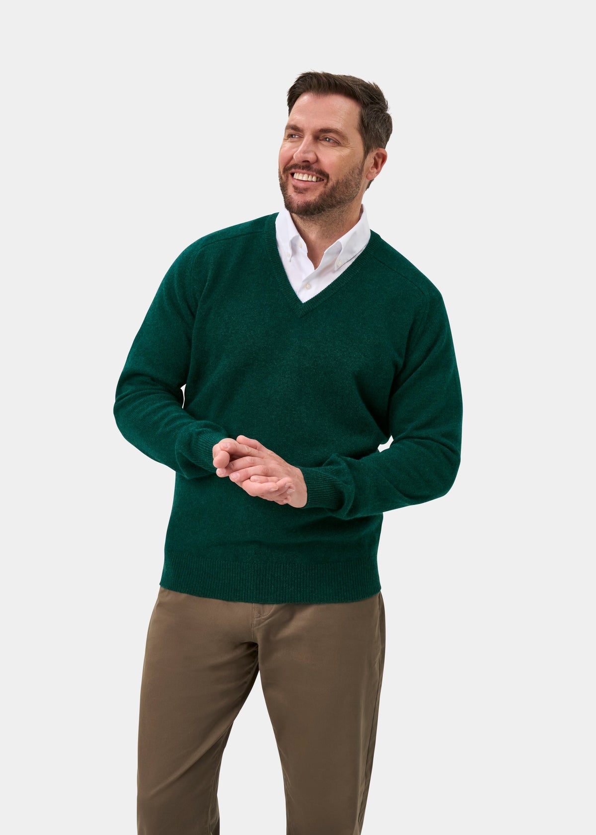 Man in Hampshire Lambswool V-Neck Jumper in Mallard, classic fit, and khaki pants, smiling on white background.