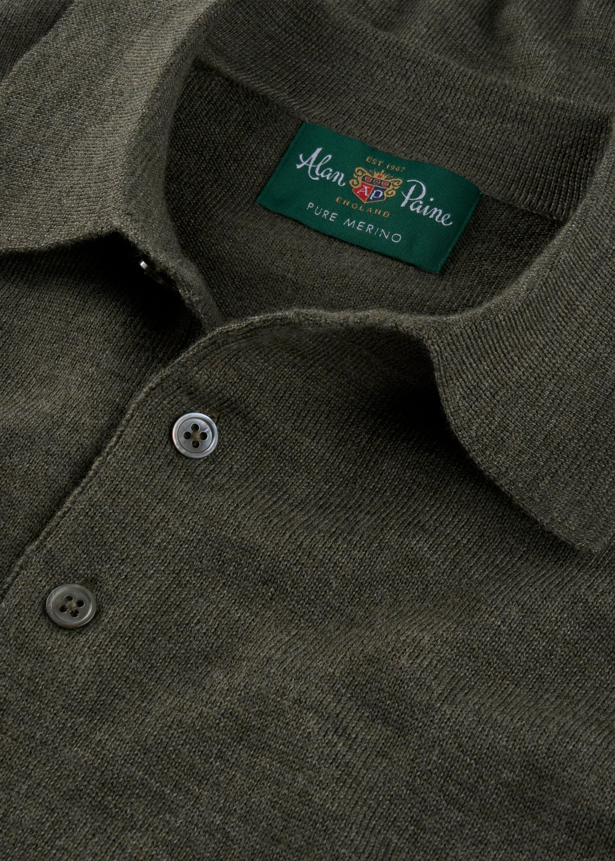 Close-up of a Hindhead Men’s Merino Wool Polo in Seaweed with buttons and visible collar branding.
