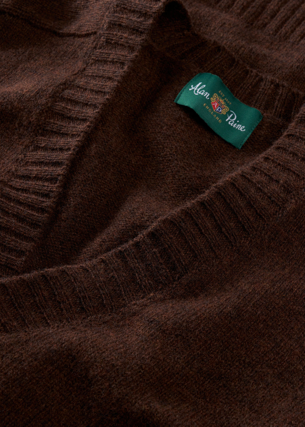 Close-up of Kinloch Supersoft Shetland Wool V-Neck Cardigan in Coffee with green Alan Paine label by neckline.