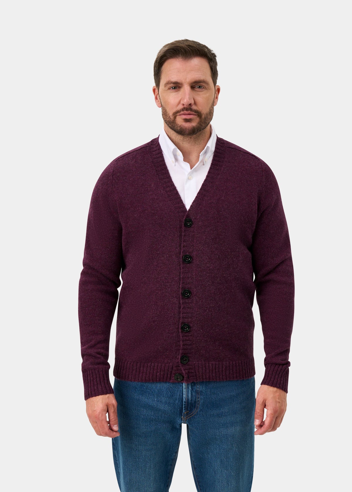 Man in Kinloch Supersoft Shetland Wool V-Neck Cardigan in Elderberry over a white shirt and blue jeans.