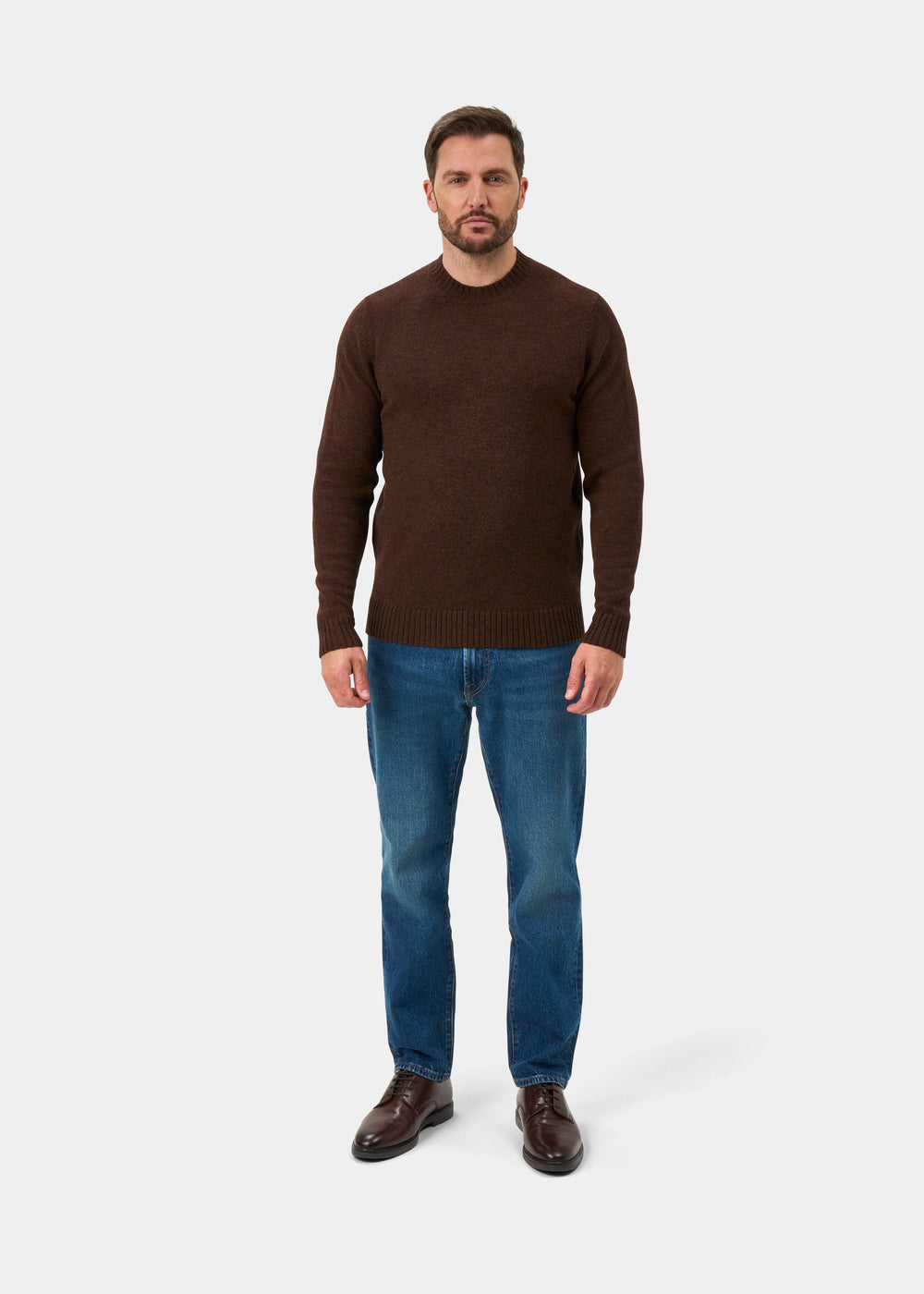 Man in Kinnadie Supersoft Shetland Wool Crew Neck Jumper in Coffee, blue jeans, and brown shoes on white background.