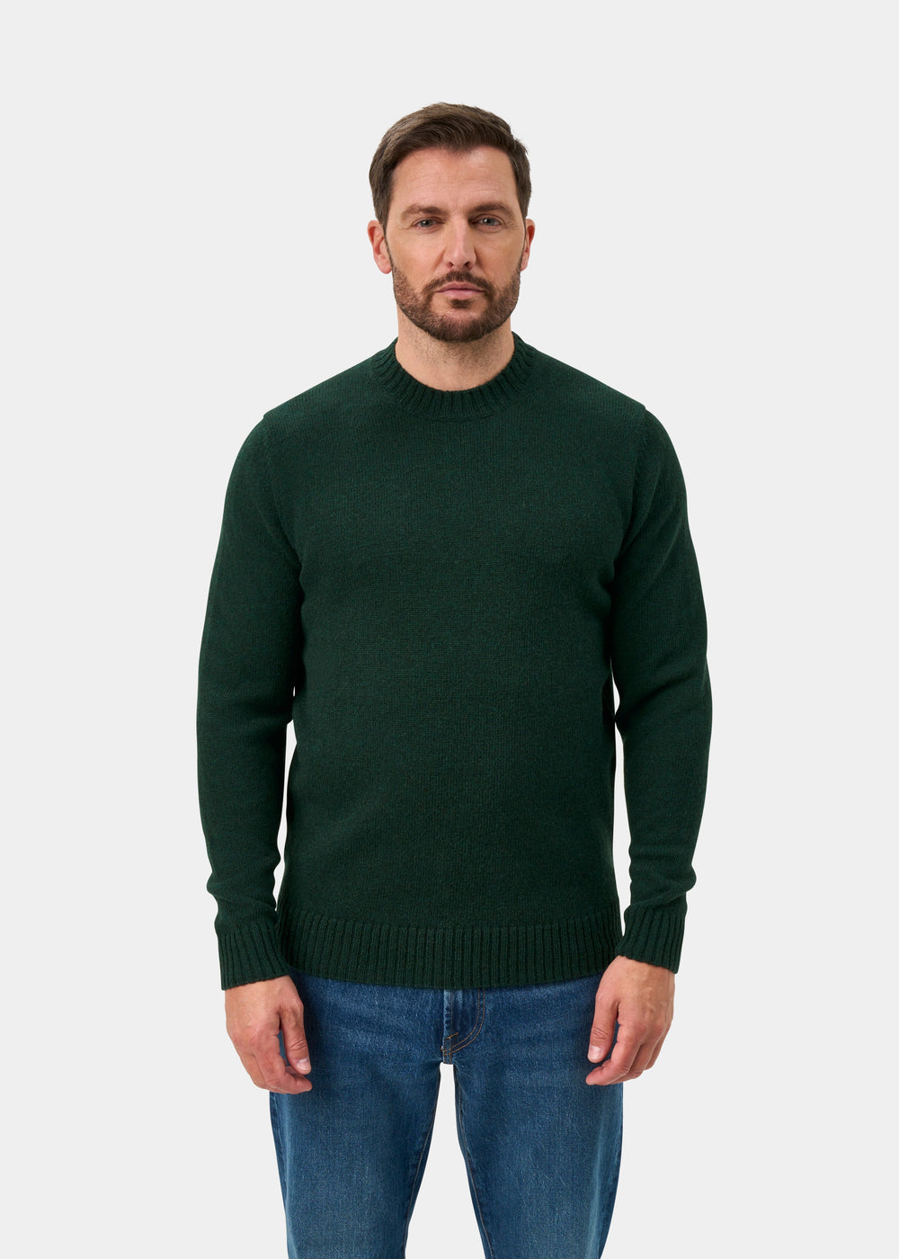 Man with short brown hair, beard, in a Kinnadie Supersoft Shetland Wool Jumper in Cossack stands by a white background.