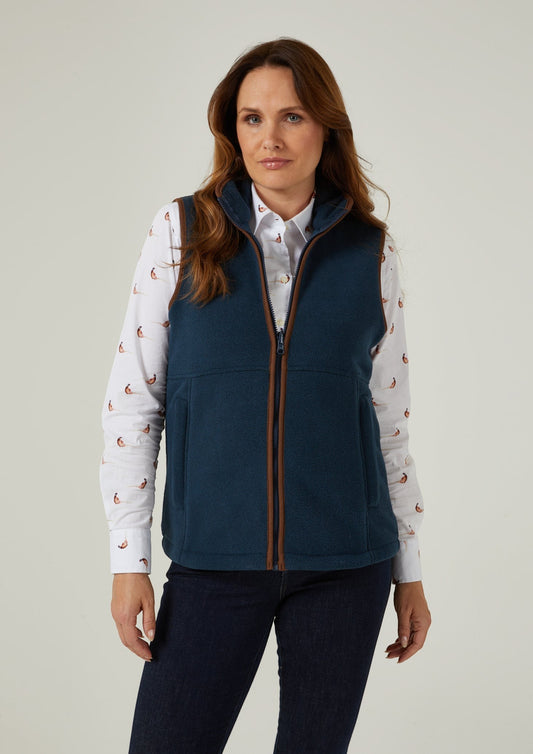 Woman in Aylsham Ladies Fleece Gilet in Blue Steel over a white sailboat-print shirt, against plain background.
