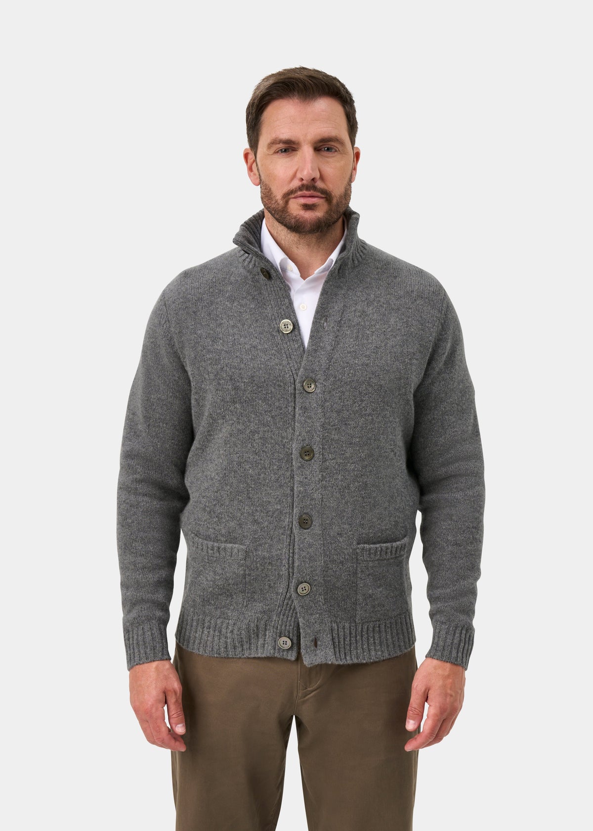 Man in a grey mix Landford lambswool jumper over a white shirt and brown pants, standing against a white background.