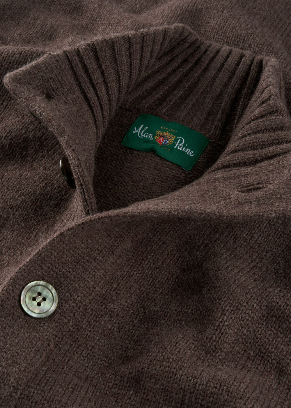 Close-up of the Landford Lambswool Mock Neck Jumper in Mocha, buttoned, with green Alan Paine label; UK-spun yarn.