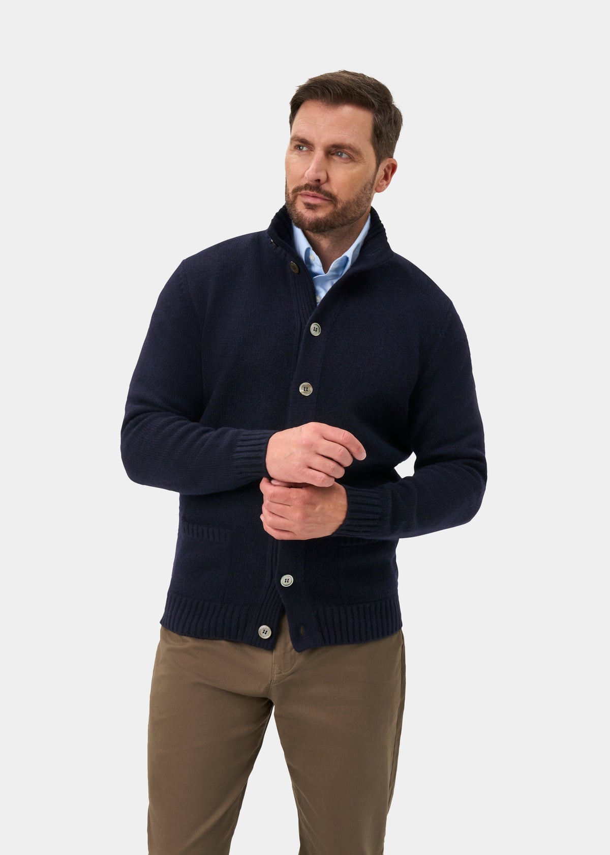 Man wearing the Landford Lambswool Buttoned Mock Neck Jumper in navy, light blue shirt, and khaki pants.