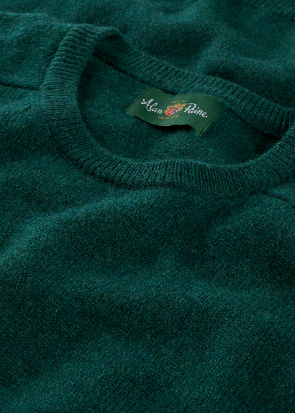 Close-up of a green sweater with a brand label on the collar.