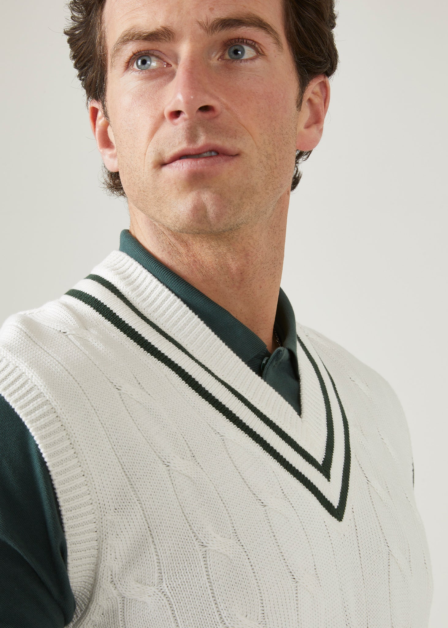 cable knit vee neck slipover in ecru with racing green trim.