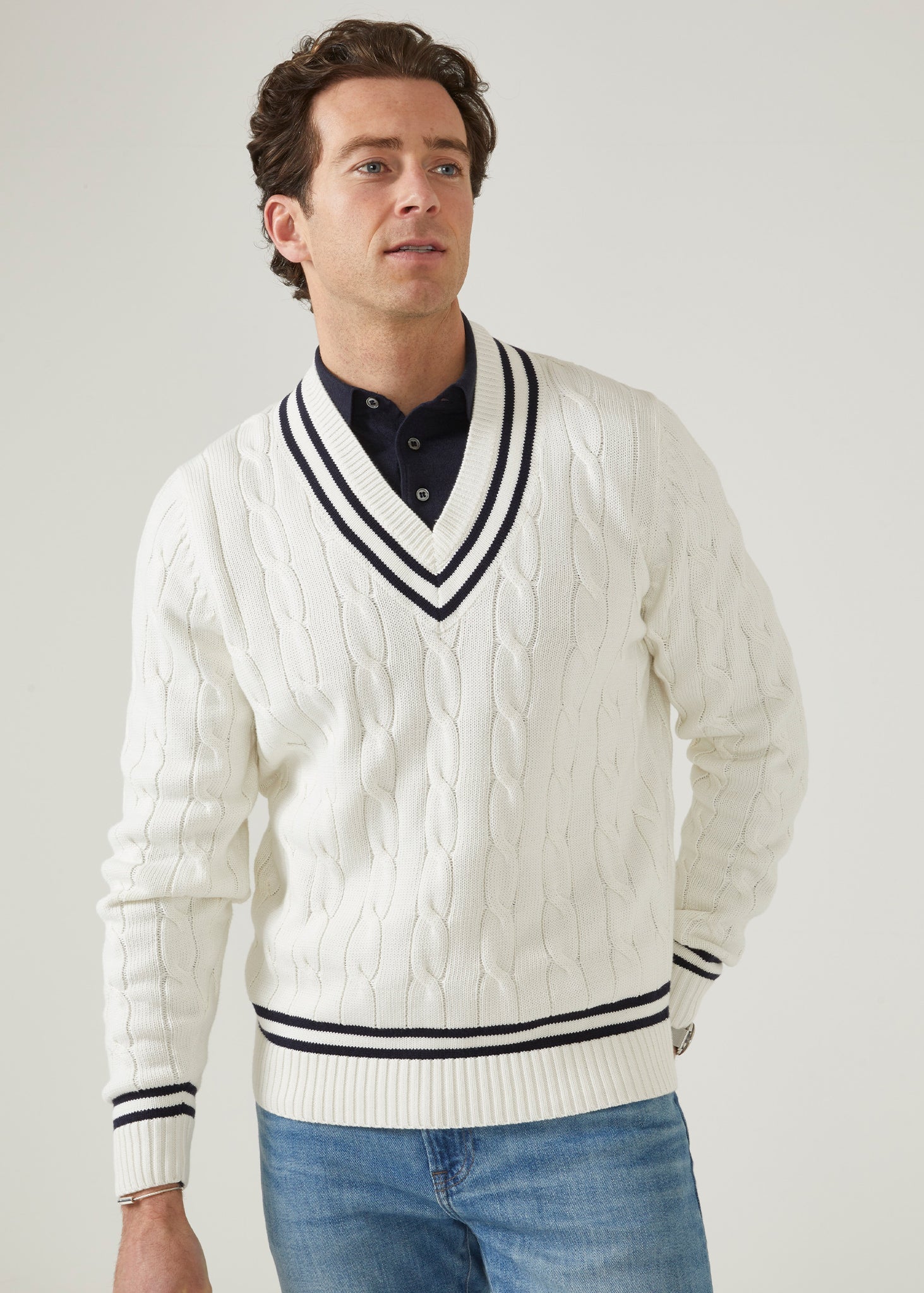 Men's ecru vee neck cable knit cricket jumper with dark navy trim.